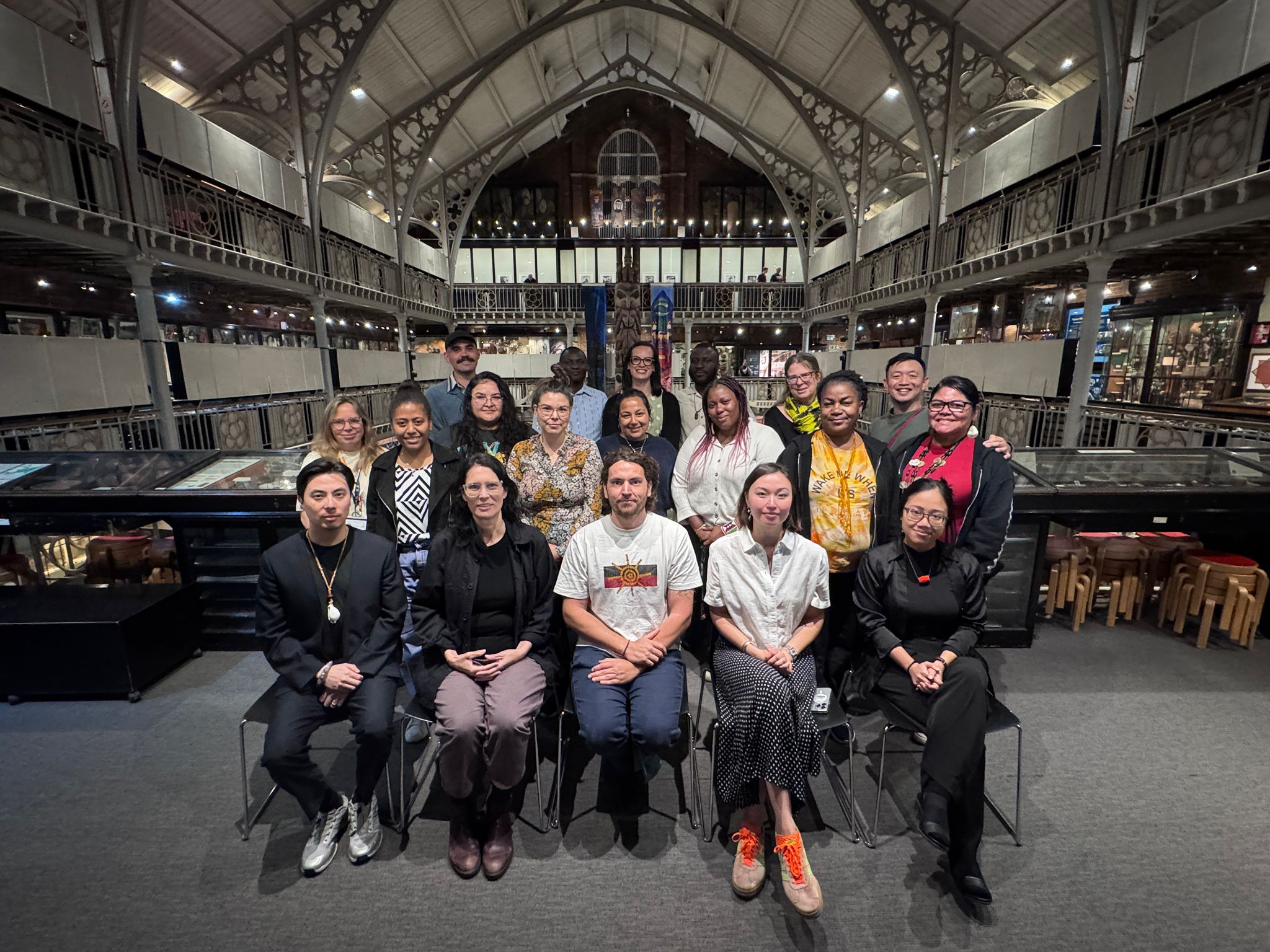 A group photo of seated and standing people within a Museum interior 