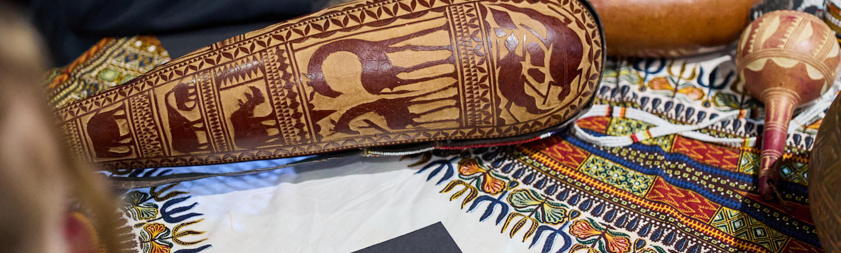 School group sitting around table with decorative gourd and black paper notebook on patterned cloth