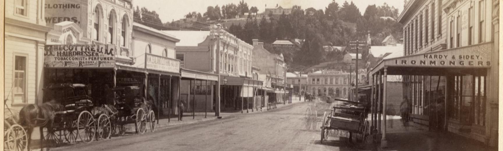 Horse-drawn vehicles stationed outside buildings on Hastings Street in Napier. Photograph by Alfred Burton for the Burton Brothers (Dunedin). Napier, North Island, New Zealand. Circa 1885.