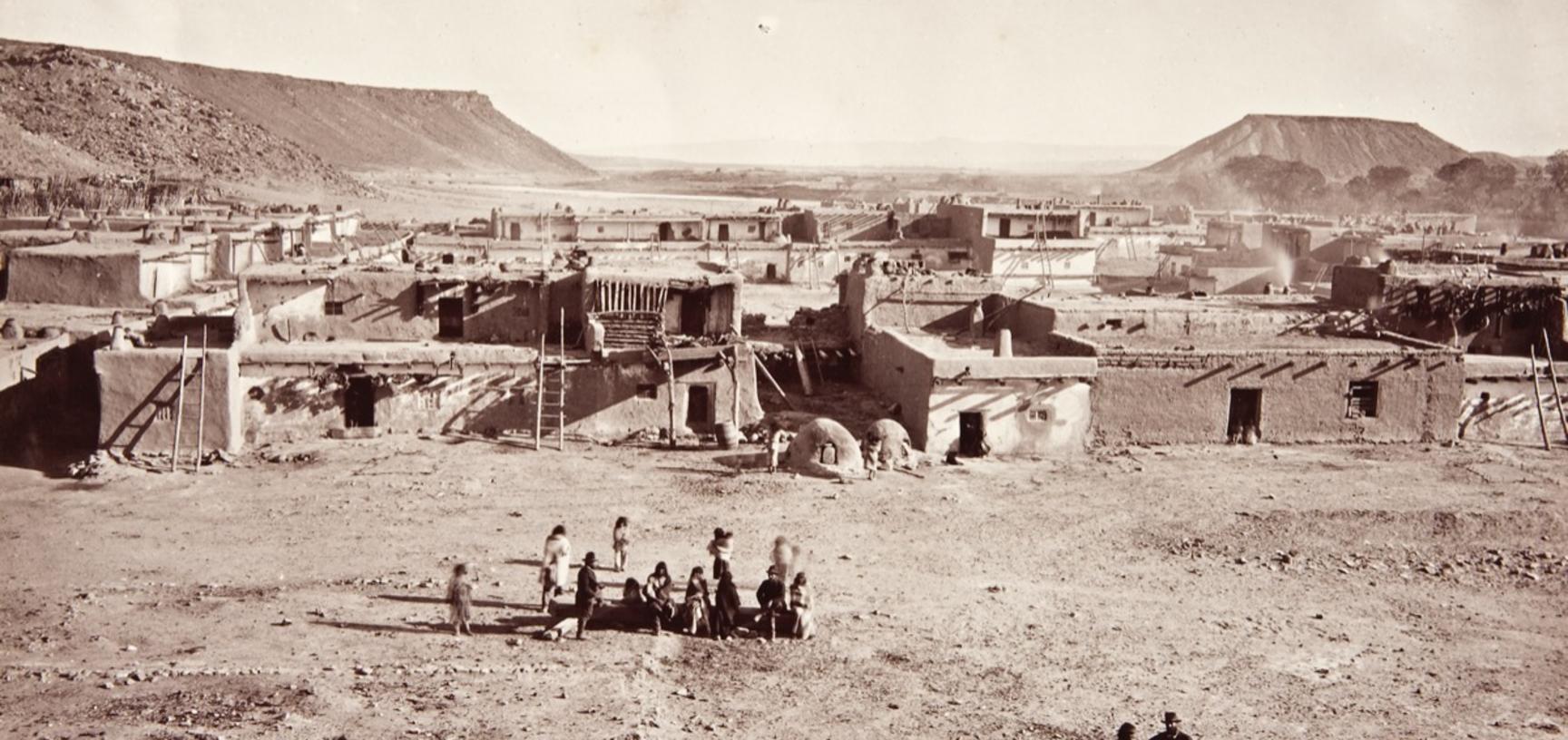 View of houses around the main plaza of San Felipe Pueblo, with the Rio Grande river visible in the distance. 