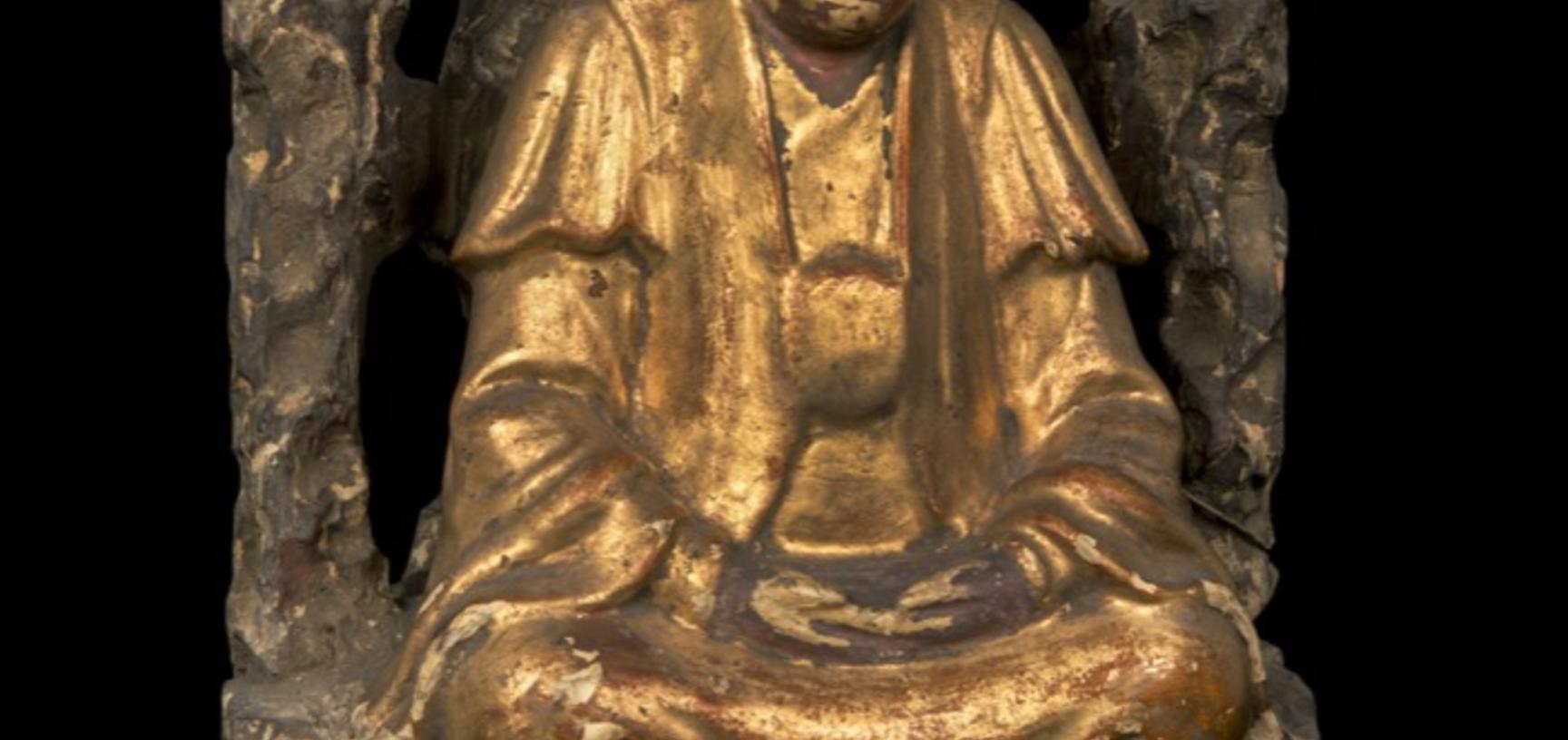 Wooden figure gilded in gold, seated under a bush.