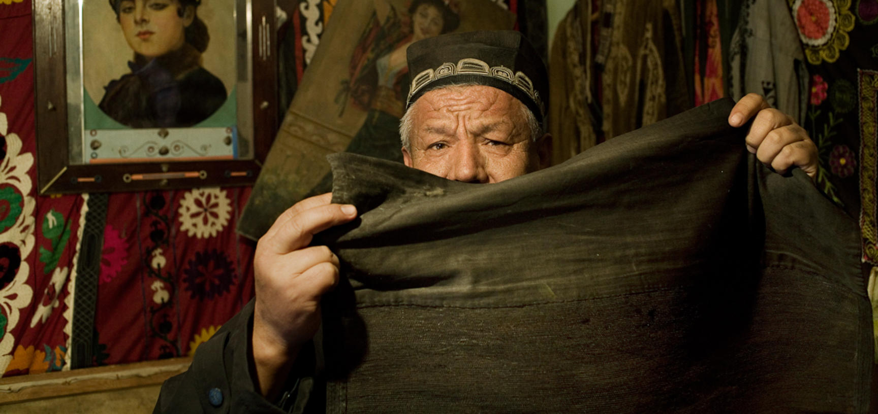 A museum-worker displaying the black hijab commonly worn by Uzbek women before the Soviet Union prohibited Islamic head-covering. Andijan, Uzbekistan. Photograph by Carolyn Drake. March 2007.