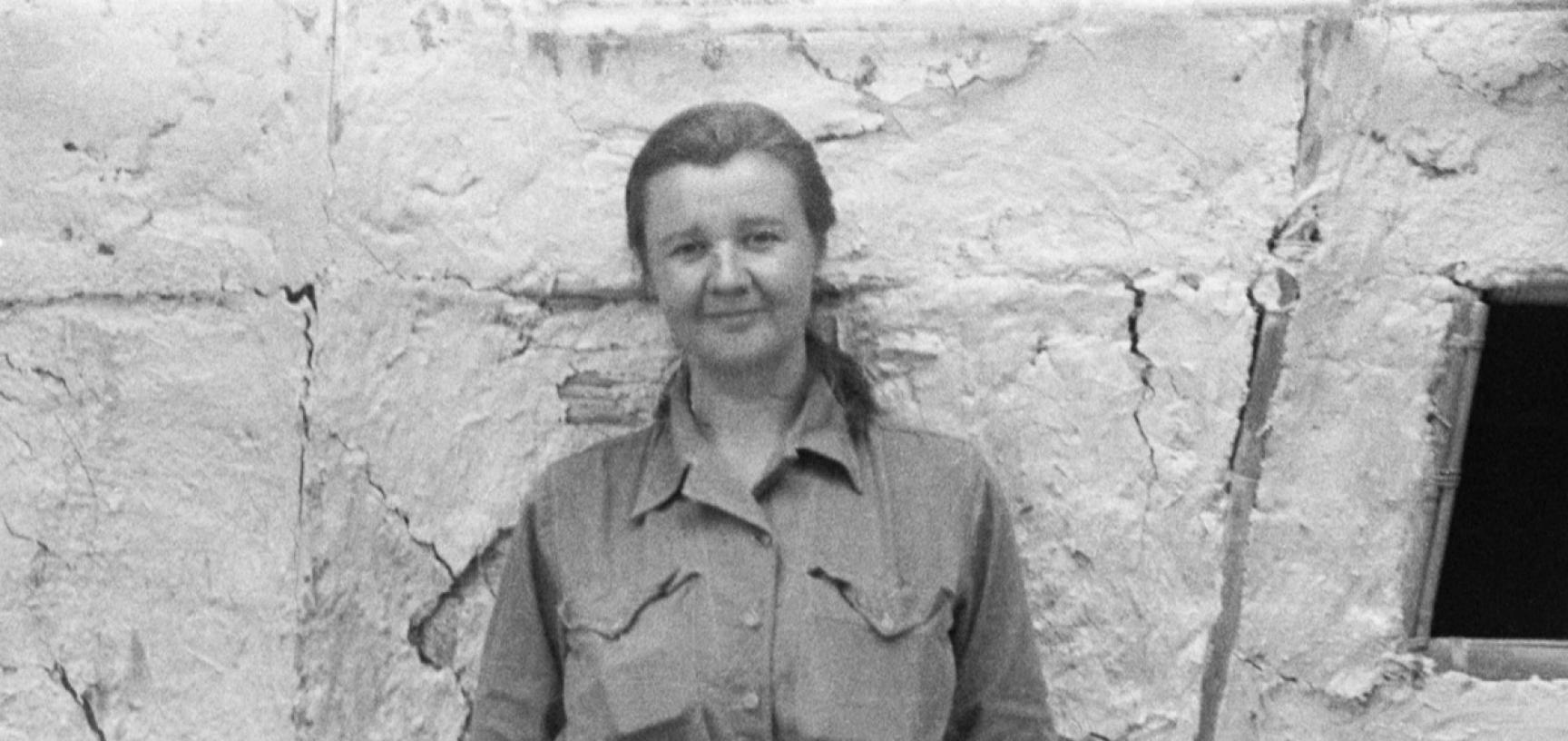 Portrait of photo Ursula Graham Bower standing next to a wall