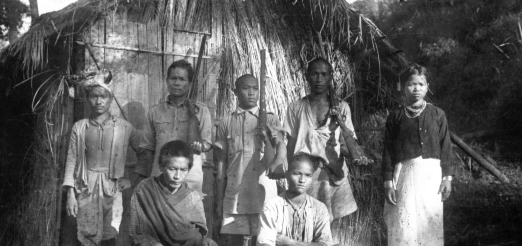 Group portrait of six men and one women, three of the men are holding guns