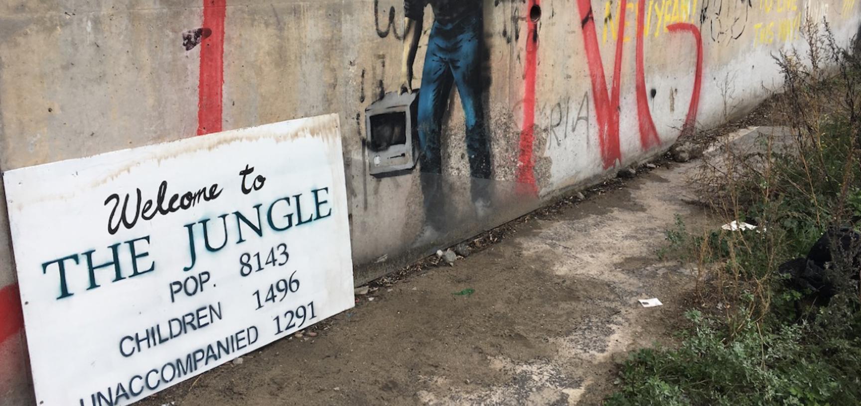Wall with graffiti and a sign on the floor: Welcome to the Jungle. Pop: 8143, Children: 1496; unaccompanied: 1291.