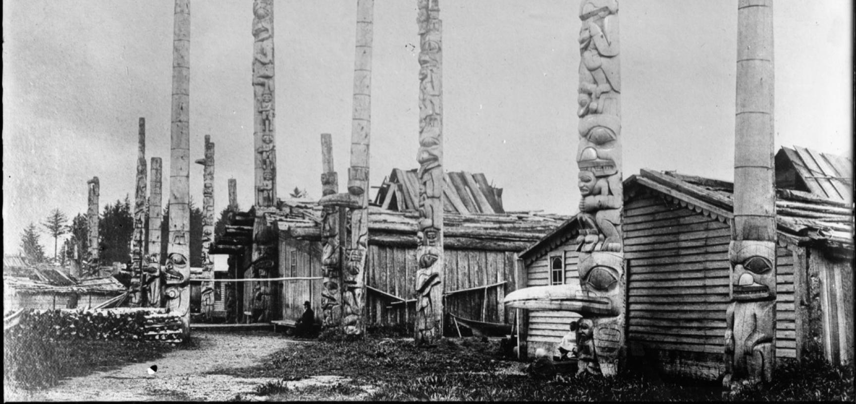 View of houses and totem poles at Masset village, with the frontal post of Star House in the foreground, now located in the Pitt Rivers Museum. Photograph by Bertram Buxton. Masset, Haida Gwaii, Canada. 1882. (Copyright Pitt Rivers Museum, University of O