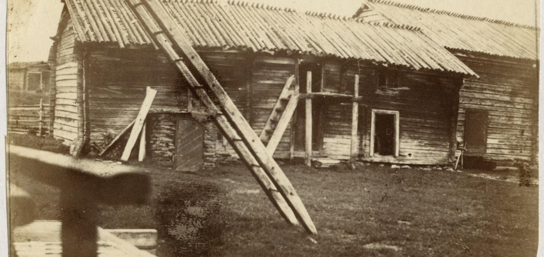 View of buildings at Sodankylä, captioned ‘Finnish homestead’, showing a storehouse for fuel and loft containing winter clothing, etc. ‘One of the peculiarities of Sodankylä is that, though it is a small village collectively, to see it all you have to do 