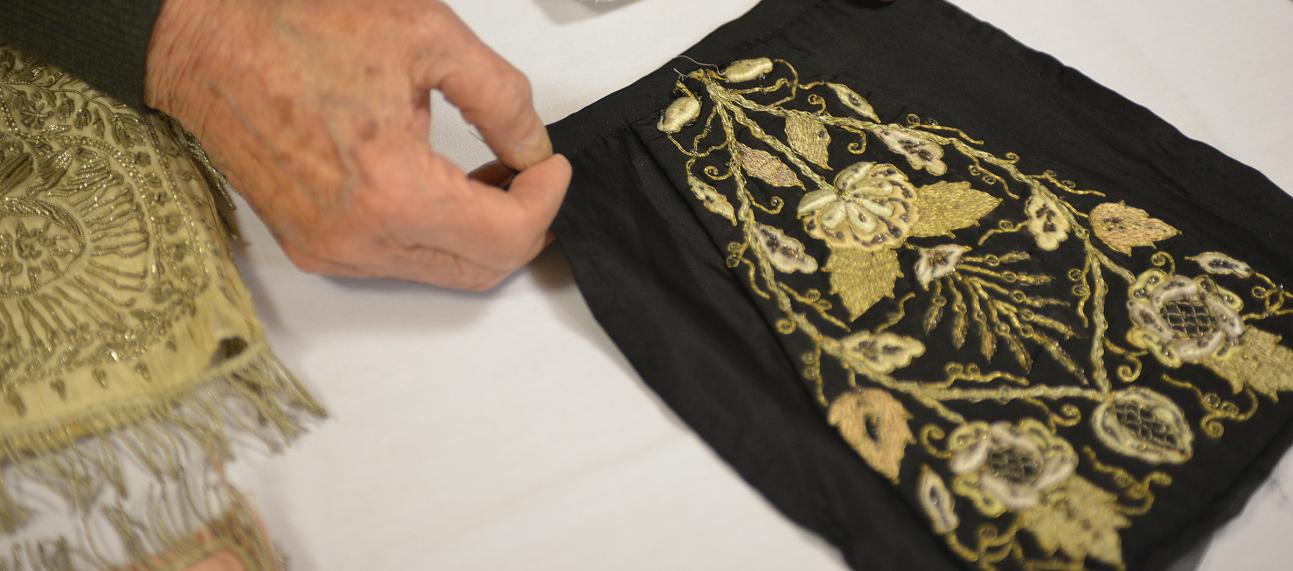 Hands holding a piece of black textile with golden embroidery