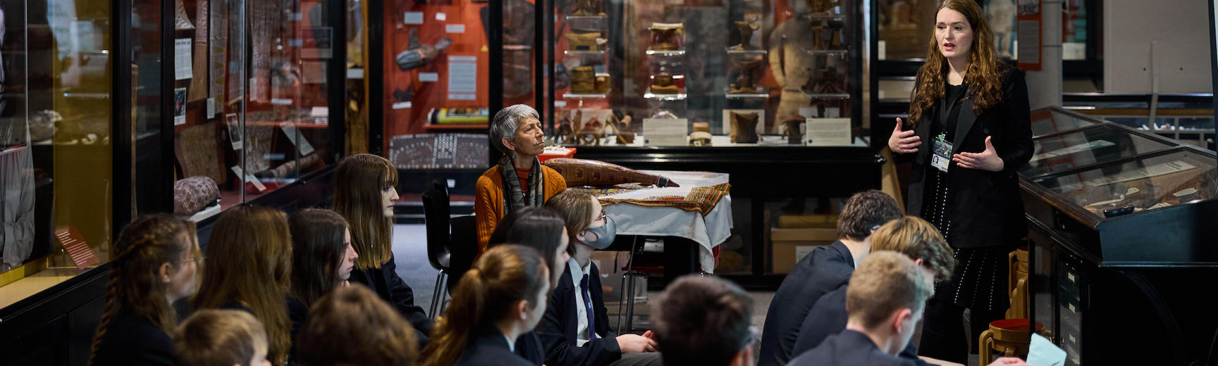 Group of students in dark school uniform sitting in museum galleries