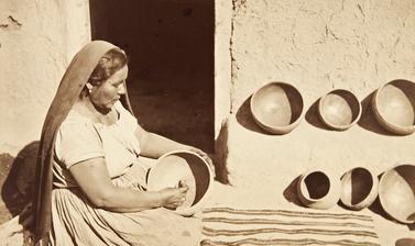 Woman polishing the inside of a large clay pot with a smooth pebble. 