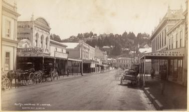 Horse-drawn vehicles stationed outside buildings on Hastings Street in Napier. Photograph by Alfred Burton for the Burton Brothers (Dunedin). Napier, North Island, New Zealand. Circa 1885.