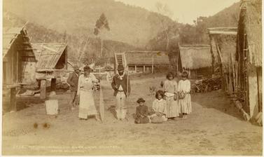Māori family pictured amidst houses at Pipiriki, a settlement on the Whanganui River. Photograph by Alfred Burton for the Burton Brothers studio (Dunedin). Pipiriki, North Island, New Zealand. 11 May 1885.