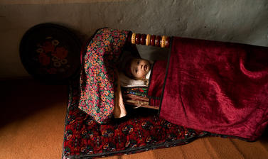 A baby in a crib on the floor of a house in the Ferghana Valley. Yaipan, Uzbekistan. Photograph by Carolyn Drake. March 2007.