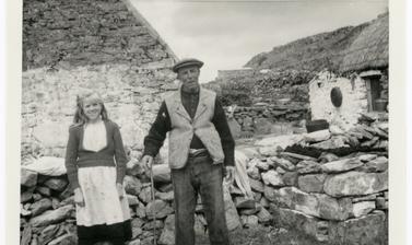 A man wearing homespun tweed and a young girl hold their hands