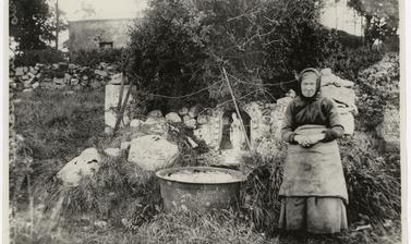 Old woman posing beside a holy well in the countryside.