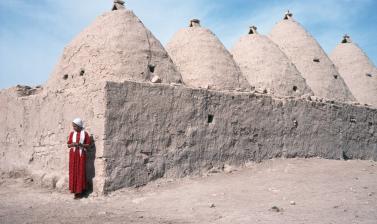 Woman outside interlinked domed houses in Anatolia