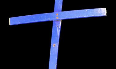 Blue wooden cross on black background