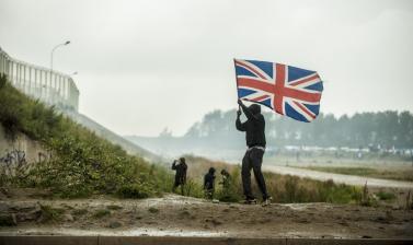 Man holding a British flag with other people in the background
