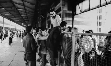 Immigrants divided by a barrier greet and kiss each other at the train station