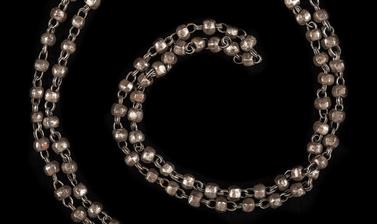 Long necklace of small iron beads linked by metal chains. 