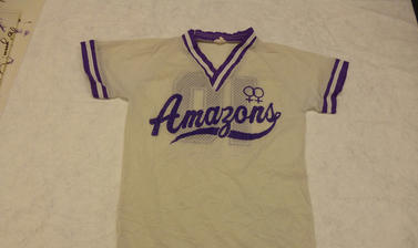 Cream sports shirt with purple Amazons team logo across the front. 