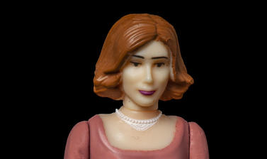Plastic model of a woman with auburn hair, dark trousers and pink jumper. 