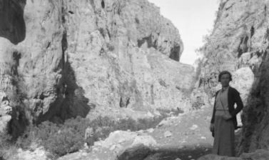 Rocky landscape with a woman standing on right hand side facing the camera. 
