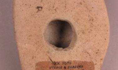 The flat back of a terracotta model, with a hole in the centre and hand-written text.