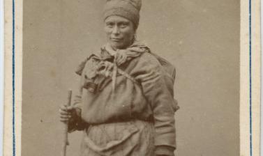 Studio portrait of a Saami woman, standing, holding a bag. Photograph by the Jørgen Wickstrøm studio. Tromsø, Norway. Circa 1870s. (Copyright Pitt Rivers Museum, University of Oxford. Accession Number: 1941.8.47)