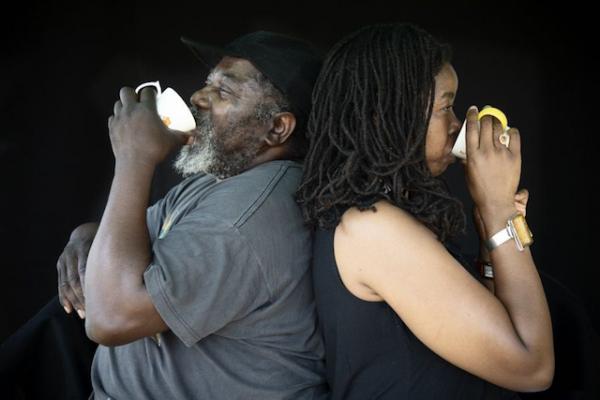 Two people back to back, both drinking from tea cups.