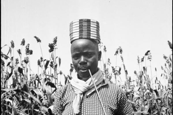 Portrait photo of a man in a field wearing a cylindrical shaped hat