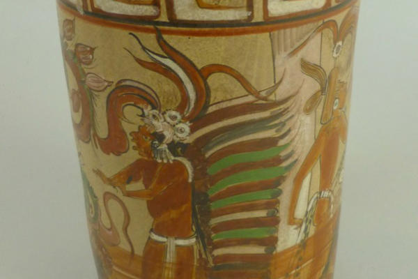 Brown cylindrical vessel painted with a cocoa tree coming out of the body of a male figure.  