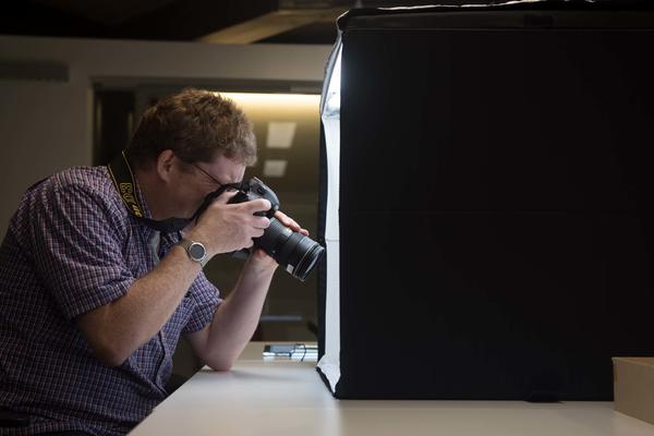 Man taking pictures using a camera and a photography light box