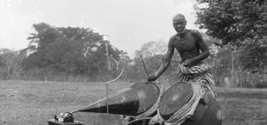 Asante man playing Ntumpane with gramophone in foreground