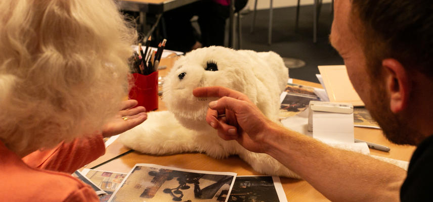 Two persons touching a seal plush toy