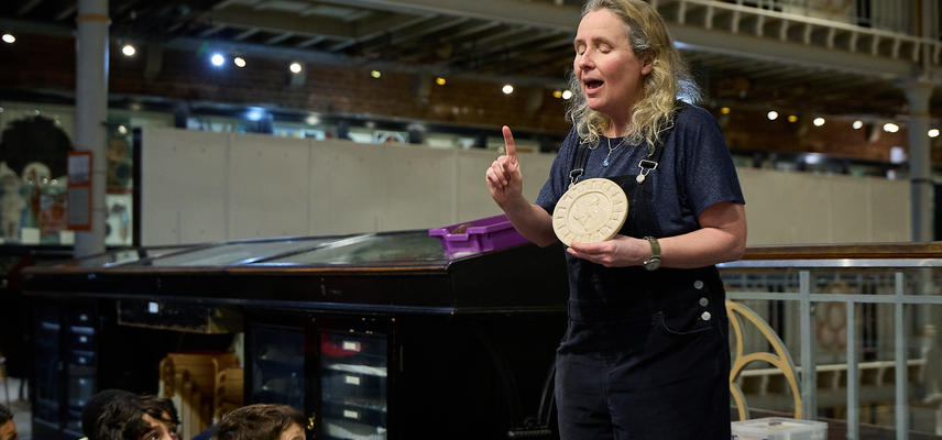Education officer holding up circular white object to show school group