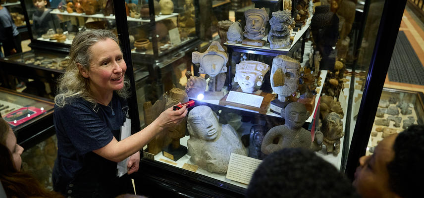 Education officer shining torch into museum case display to show school group
