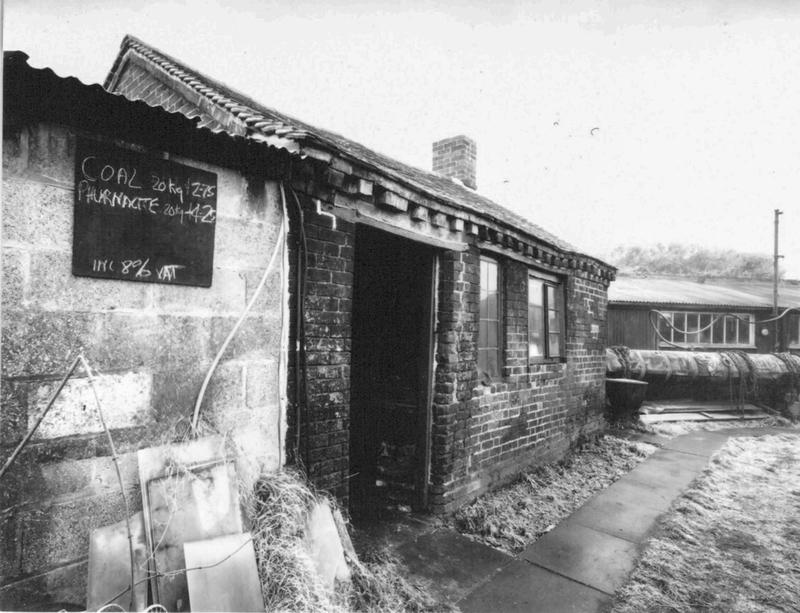 Black and white picture of a single story brick building with corrugated iron roof.