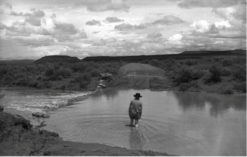 Black and white image of man wading in lake