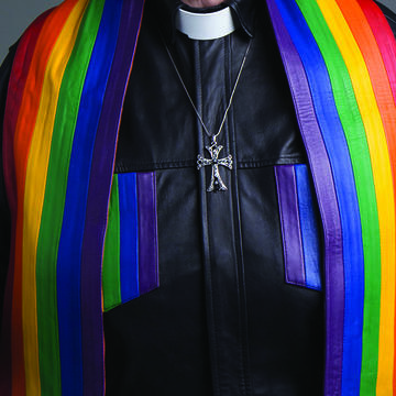 Close up of vicar's chest wearing silver cross and rainbow stole