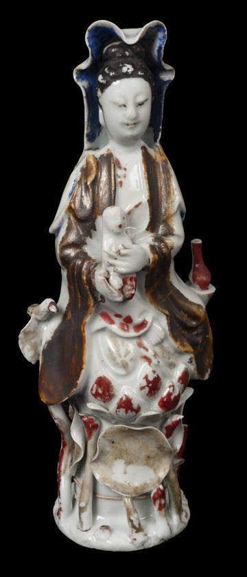 Greyish-white porcelain ornament depicting a goddess in human form, with painted details in colour.  