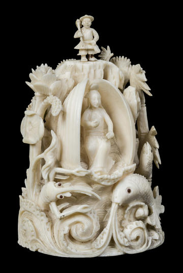Carved ivory female and male figure set in a landscape of rocks, trees, waves.