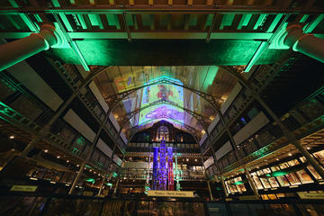 View of darkened museum galleries with green uplighting and coloured images projected onto the ceiling.