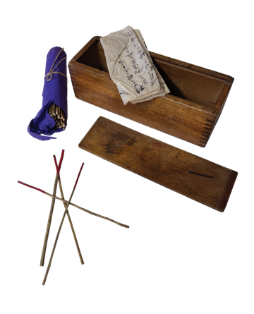 An open rectangular box with a bundle of sticks and folded paper