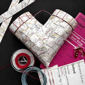 Woven V shape using strips of old maps against a background of maps and cut strips of maps