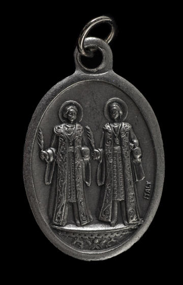 Oval metal pendant with two figures dressed in robes, each with a halo around their head.