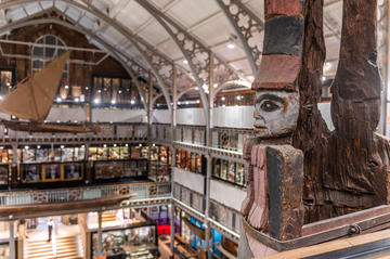 View of Pitt Rivers Museum from top floor with totem pole in foreground and suspended boat in background