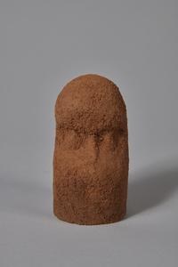 A small roughly head-shaped figure made of laterite (red mud)
